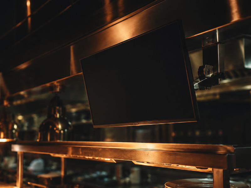 Kitchen display screen mounted above the pass in a working restaurant kitchen